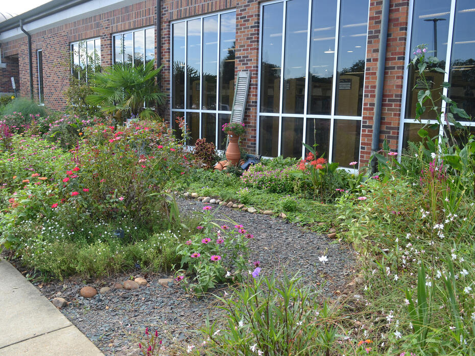 A gravel trail cuts through a garden in front of a building.