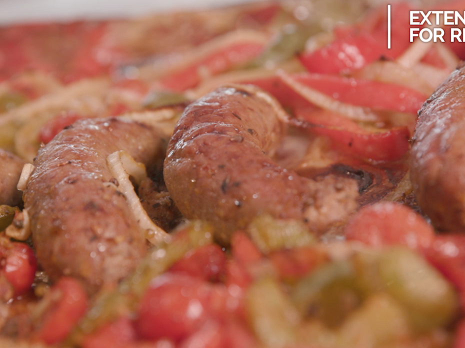 A pan of prepared Italian sausages with onions and green and red peppers.