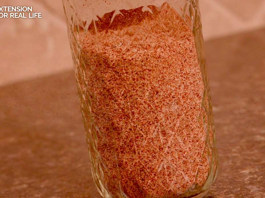 A pint glass jar filled with homemade taco seasoning sits on a kitchen countertop.