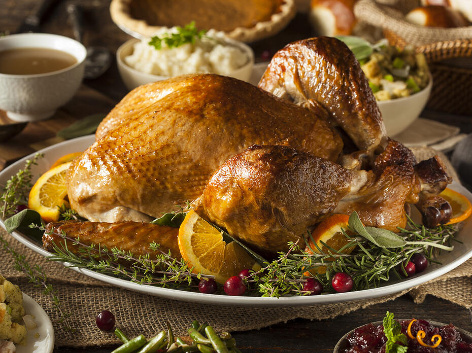 roasted turkey on a platter with herbs, cranberries, and orange slices