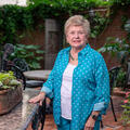 A person standing in a garden beside a plant. 