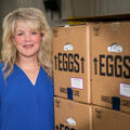 A person standing beside boxes of eggs. 