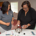 A person using a measuring spoon while another person looks on.