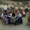 Groups of people seated and standing in a conference room.