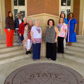 A group of people standing in a V shape on outdoor steps.