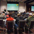 A panoramic image of a large crowd of people with two large screens in the back.