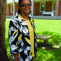 Woman in glasses smiles in front of brick building