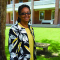 Woman in glasses smiles in front of brick building