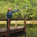 Woman standing on pier in lake holding cup of water