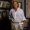 A man stands behind a table with 2 small bags labeled “Two Brooks Farm.” 