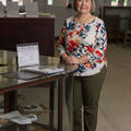 A smiling woman stands beside a museum display.