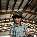 A smiling young man astride a horse and wearing a helmet.