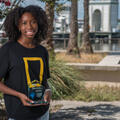 A young woman smiling and holding a trophy.