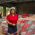 A woman wearing a hard hat standing beside a stack of pallets.