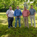 Four people standing outside, hands in their pockets.