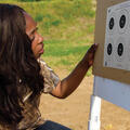 A young woman kneels down next to a board with targets.