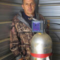 A man stands behind a piece of machinery.