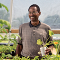 A man holding a styrofoam cup with a plant sprout.