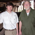 An older man and a young man stand next to each other smiling.