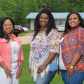 Three smiling women stand next to each other.