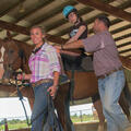 A girl on a brown horse led by a woman and man.