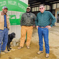 Three men and a black dog stand in front of a sign that reads "Dantzler Phillips Pilkinton."