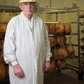 A man stands in front of a rack holding meat.