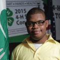 A young boy next to a 4-H flag.