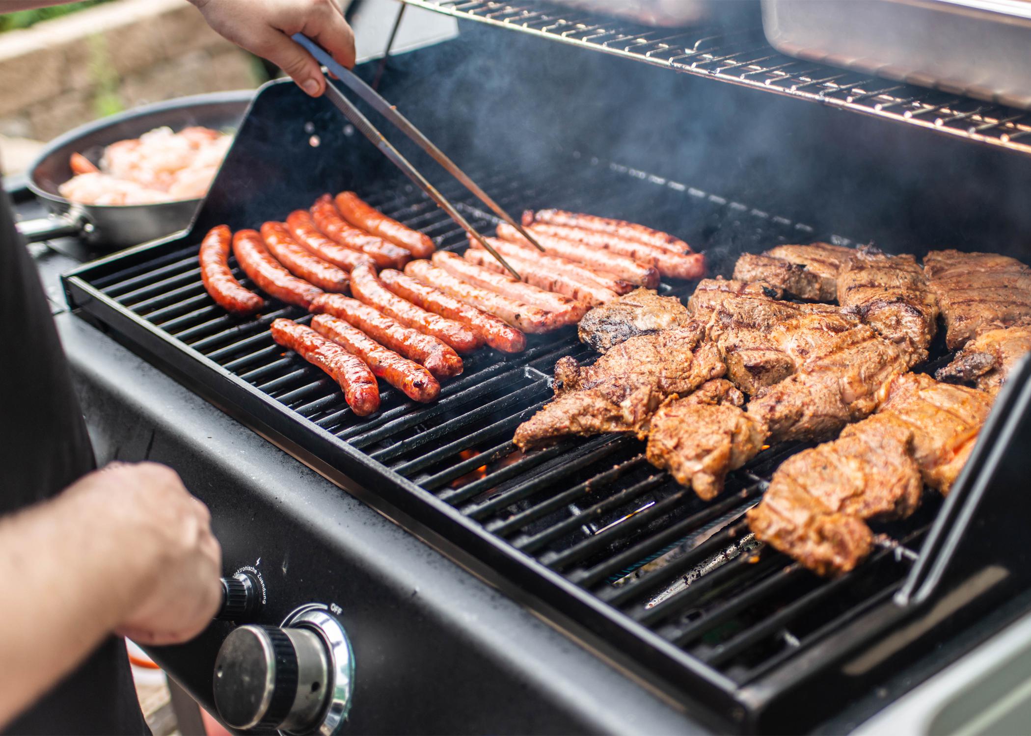 Grill with hotdogs and chicken on it