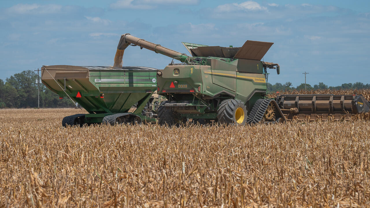 Corn is transferred in a field from the harvester to a grain cart.