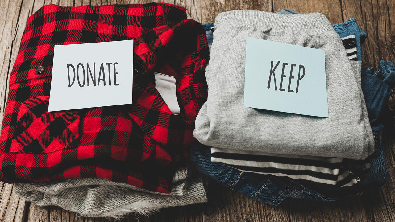 Two piles of clothes. One with donate on it, the other with keep.