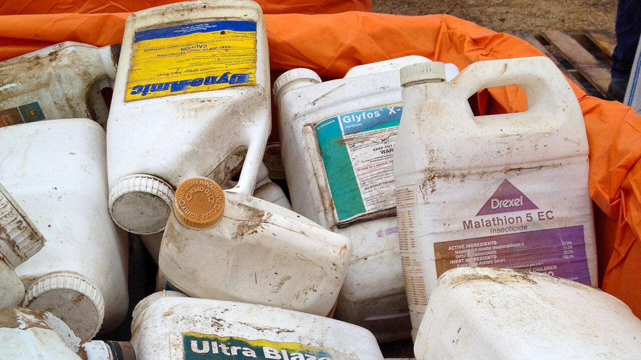 Pile of used agricultural chemical containers in an orange-lined bin.