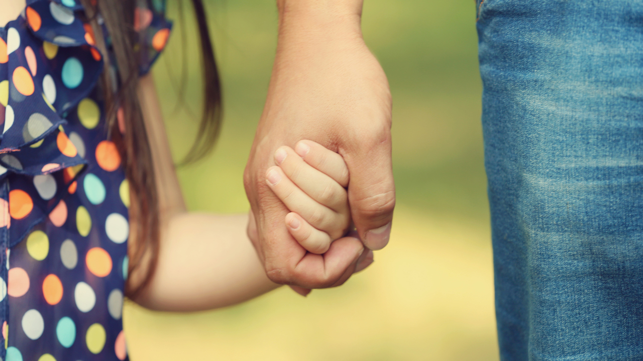 Close up picture of an adult holding a child's hand.