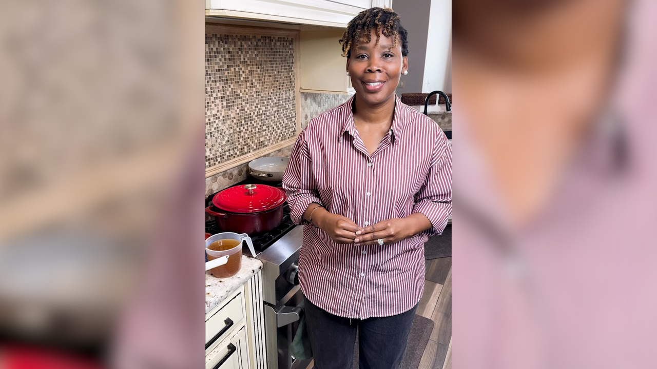 A person stands in a kitchen in front of the stove.