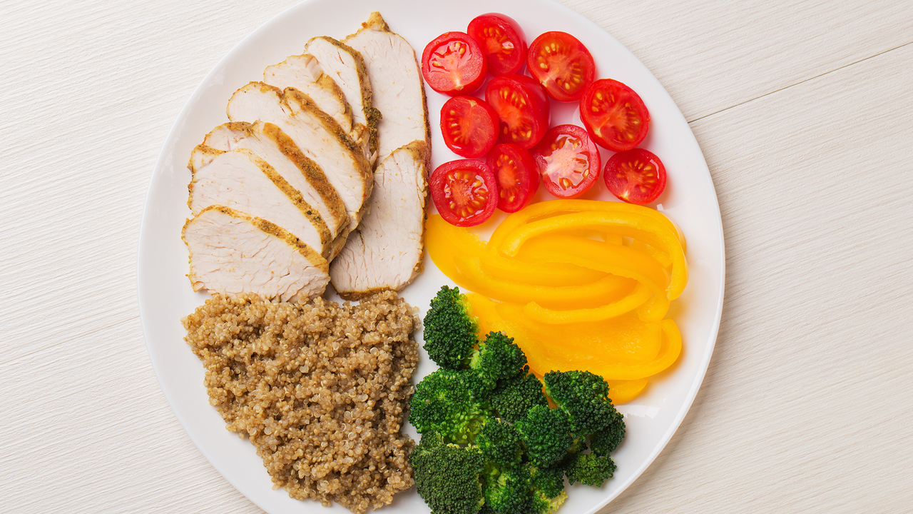 A plate with tomatoes, yellow peppers, broccoli, quinoa, and chicken.