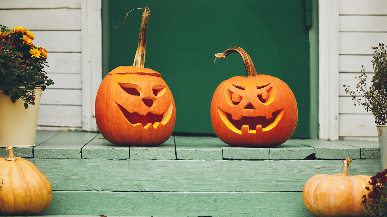 Two carved pumpkins on a front porch