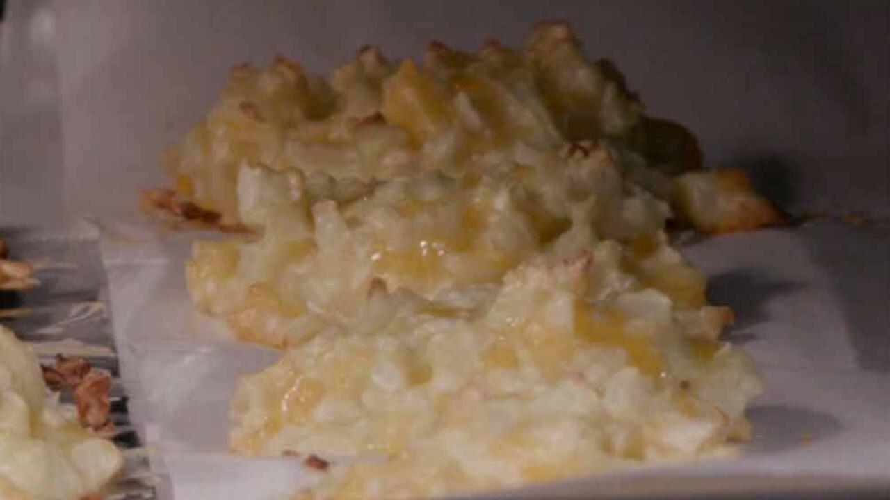 Cauliflower and cheese tots on a parchment-paper lined baking sheet.
