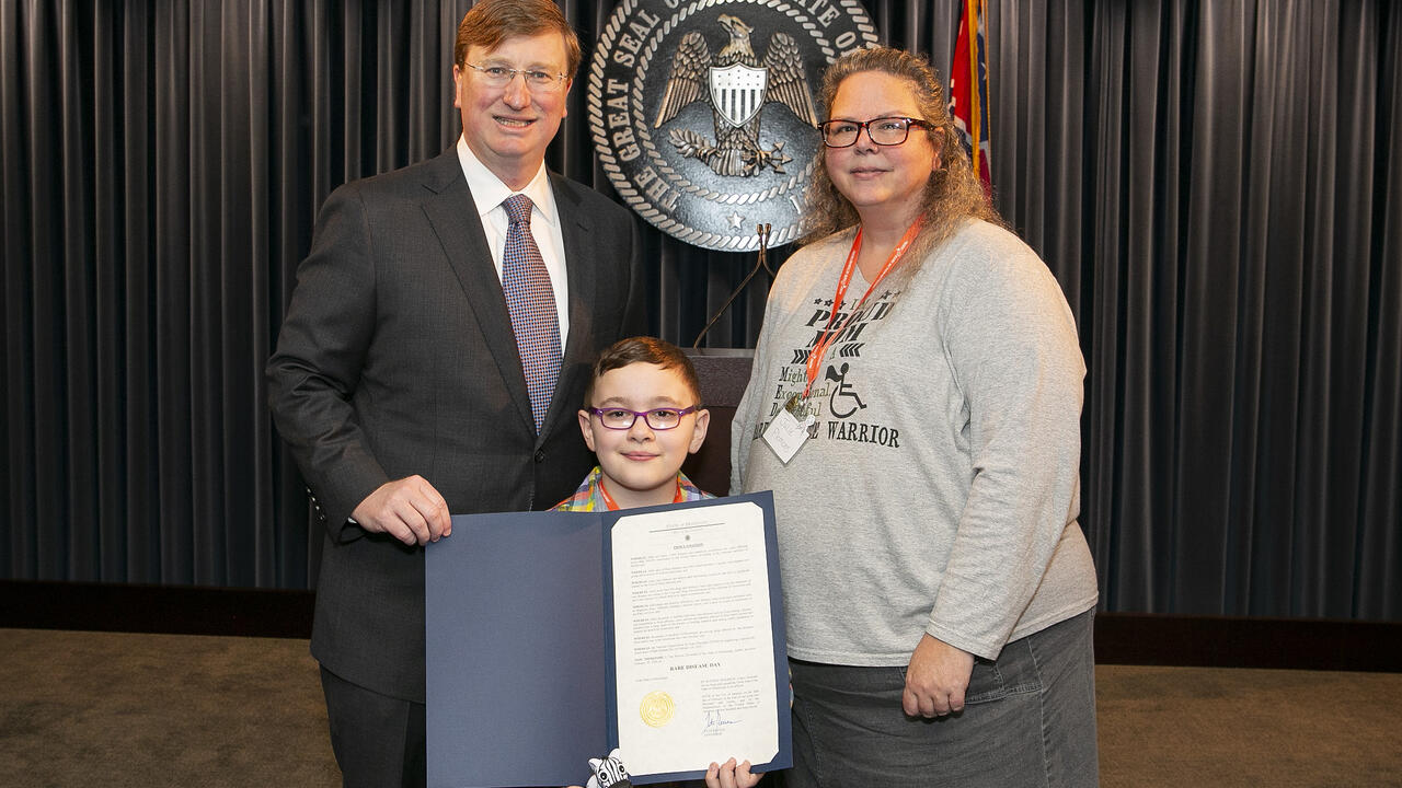 Three individuals pose with a newly signed proclamation.