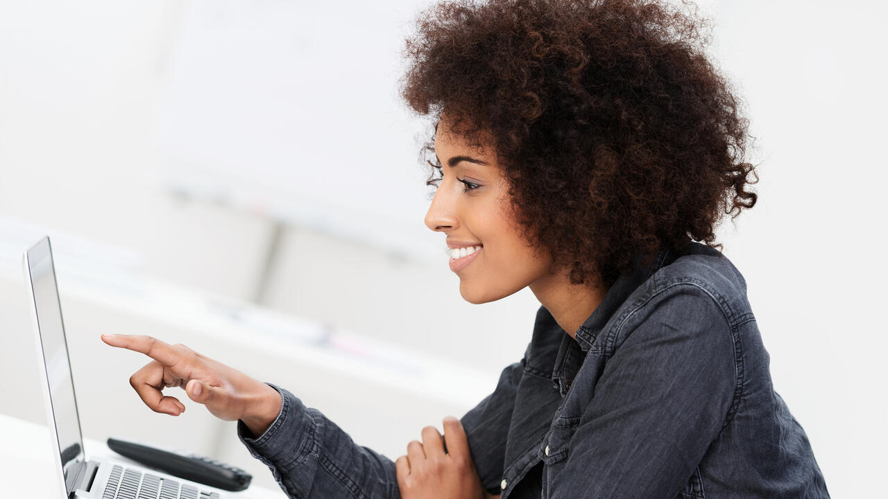 Woman points at computer screen.