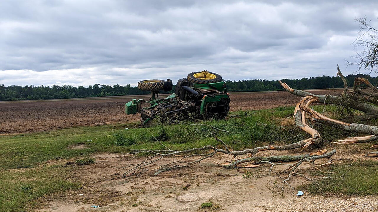Green tractor flipped on its side in a field.