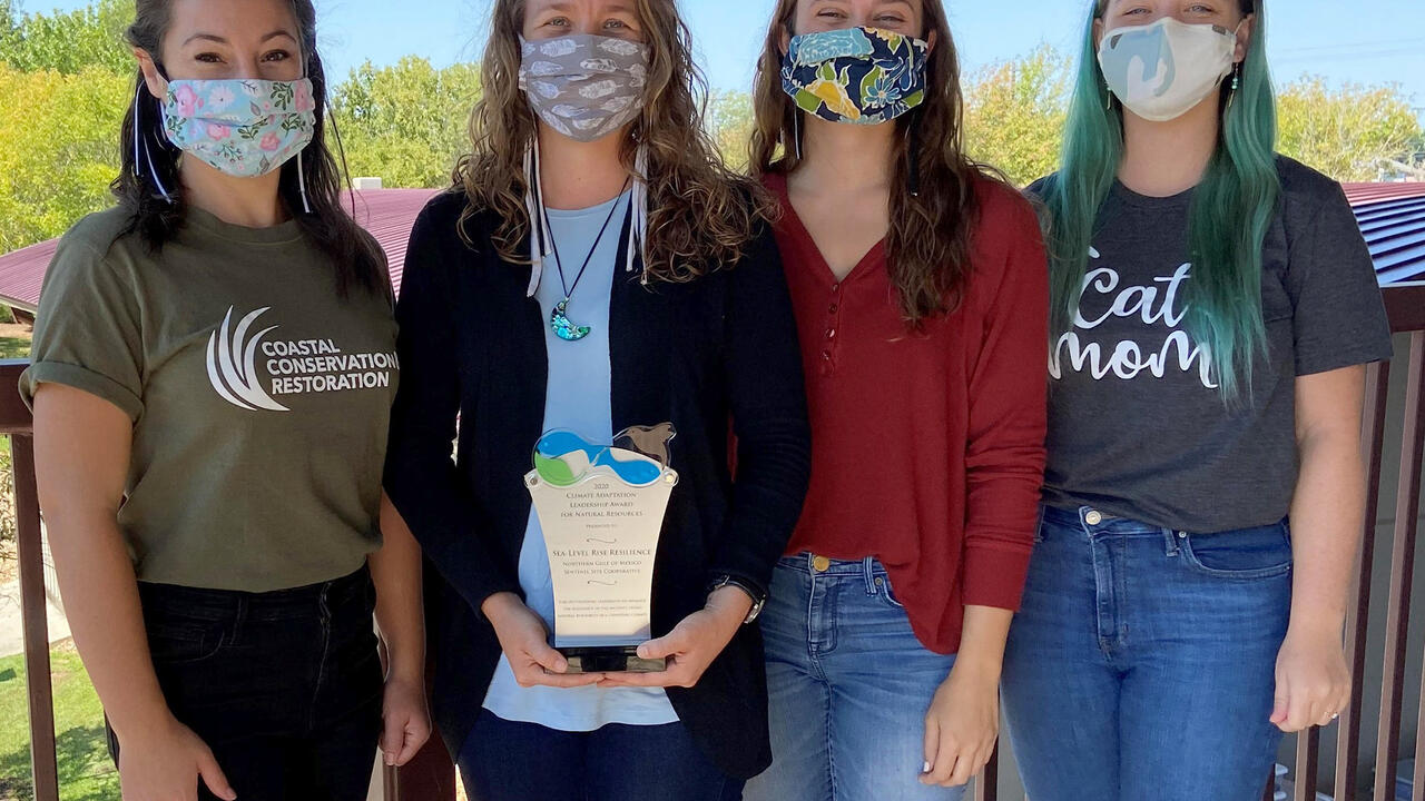 Four women pose with an award.