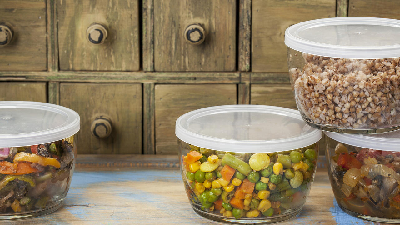 Four glass containers with plastic lids contain food leftovers.