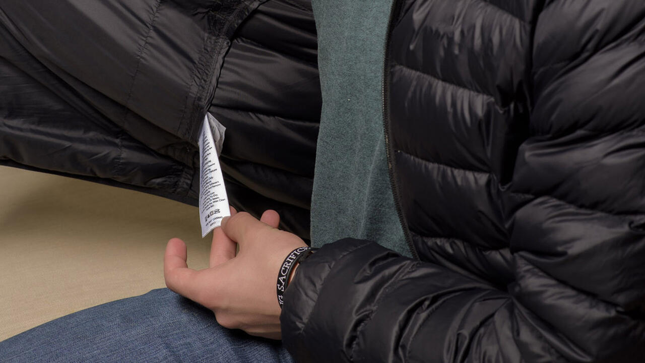 A hand holds onto the tag inside a garment.