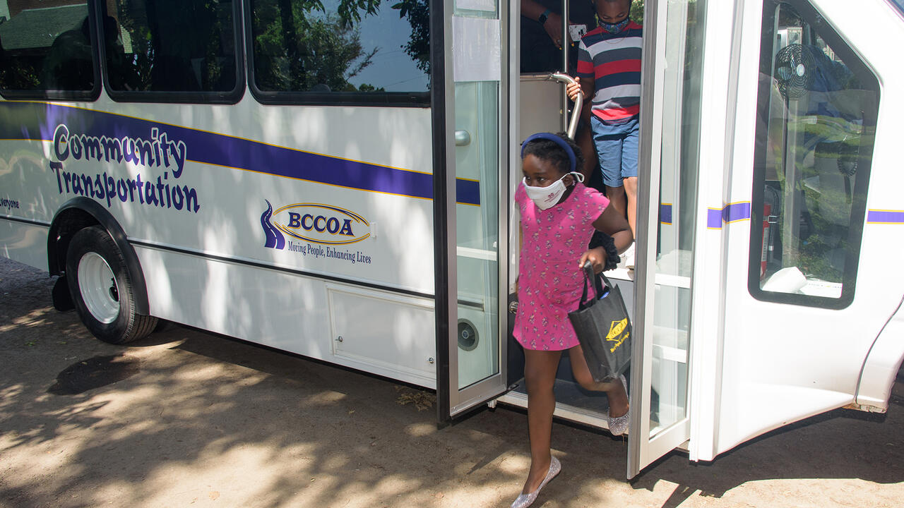 Two people step off a bus.