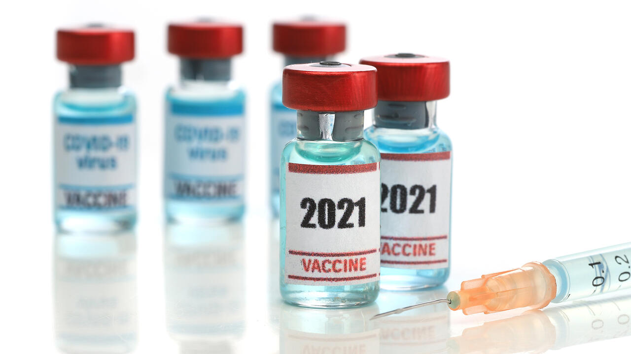 Two medical ampoules of COVID-19 vaccine with a syringe.