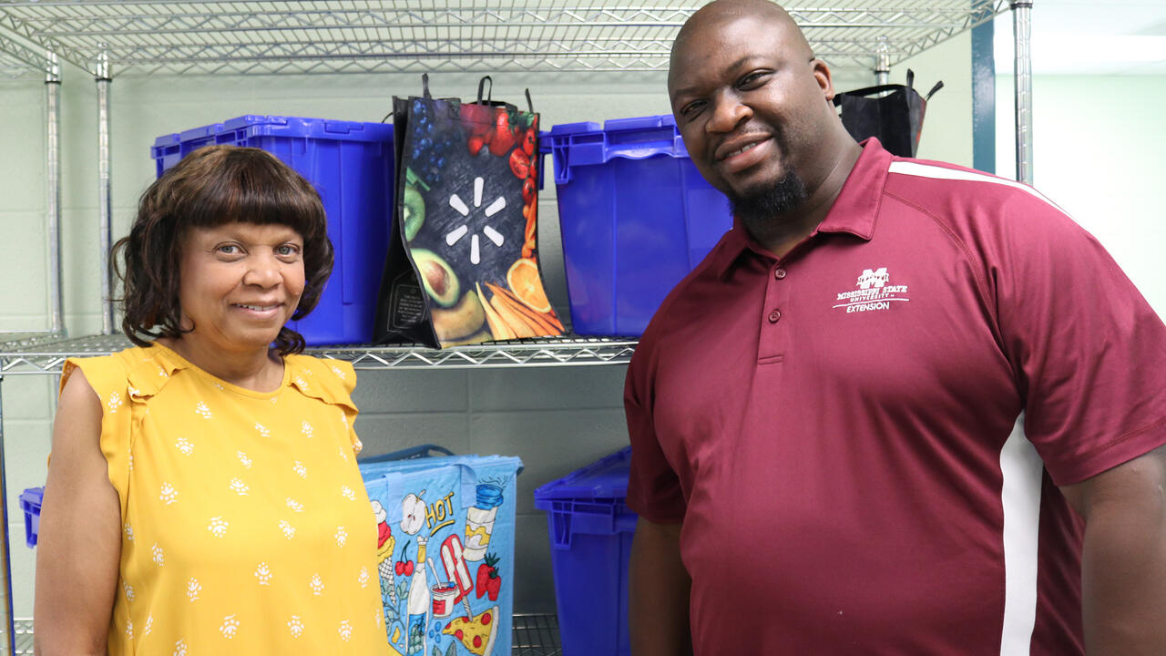 A woman and a man pose in front of shopping bags and blue crates.