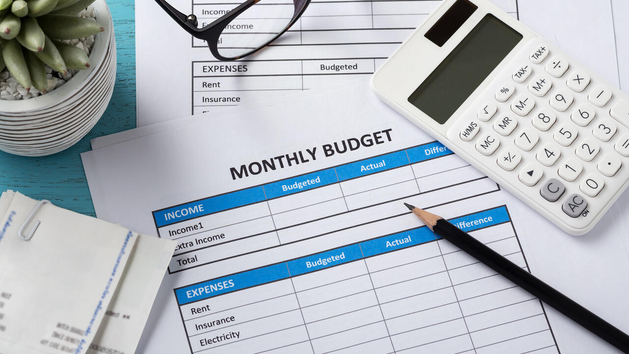 Calculator, pencil, receipts and monthly budget sheets on a table.