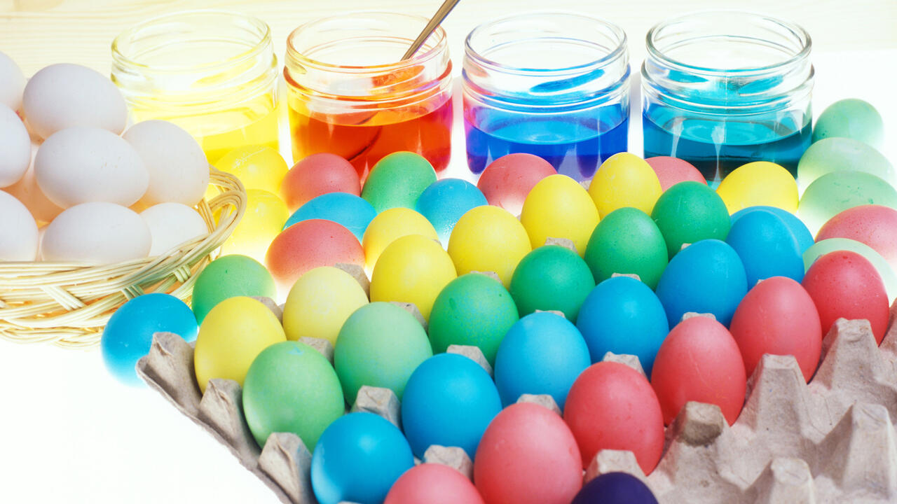 Dye, eggs and dyed eggs on a counter.