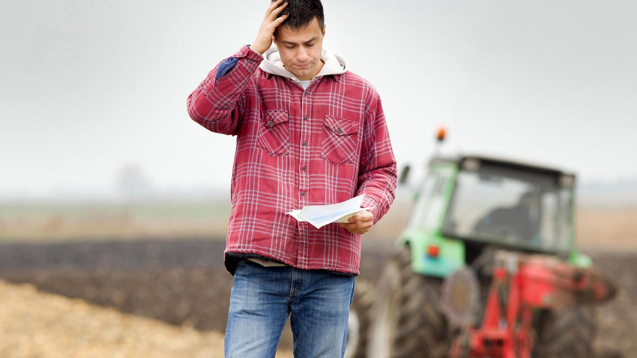 Man on a farm holding a baseball cap.