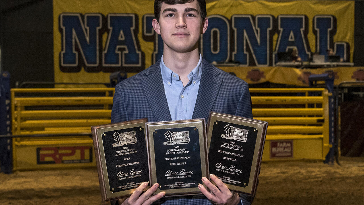 A young man holds three plaques.	